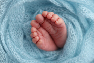 Baby foot on blue soft coverlet, blanket. Close-up of tiny, cute, bare toes, heels and feet of a newborn girl, boy. 