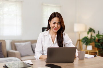 Asian female hand holding coffee cup with laptop financial management and checking planning and online at home office
