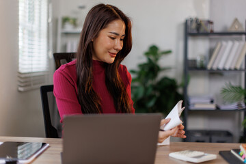 Calculator, budget and asian woman in home office with laptop, financial management and checking bills. Remote work, bookkeeping and freelancer with tax invoice, planning and online project cost.