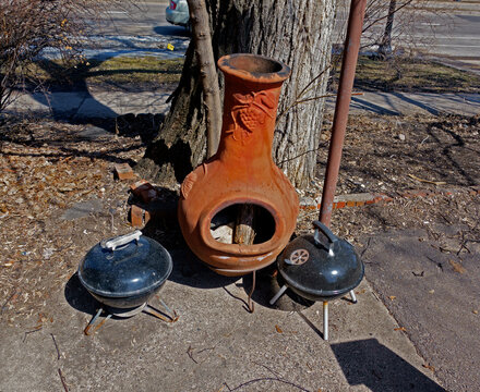 Chiminea cooker and heater dwarfing two Weber Charcoal Grills on an apartment patio. St Paul Minnesota MN USA