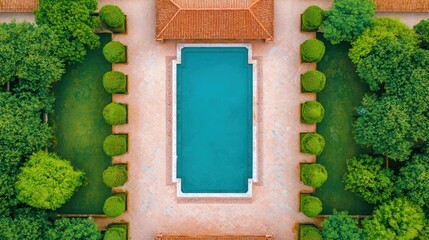 Aerial view of a serene swimming pool surrounded by lush greenery and terracotta rooftops, creating a tranquil outdoor oasis.