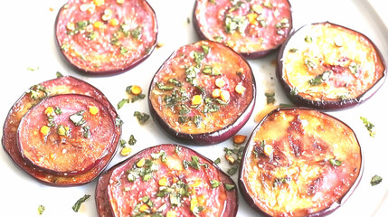 Overhead Shot of Roasted Eggplant Slices with Herb and Garlic Seasoning on White Plate