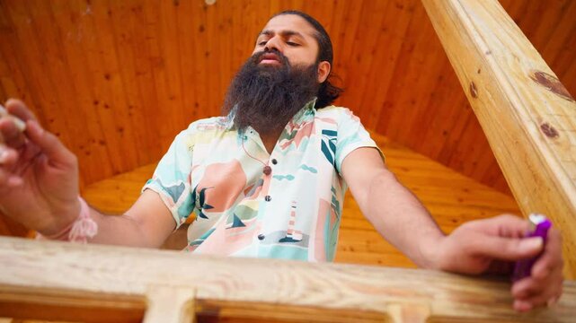 Bearded thinker smoking leans on wooden railing