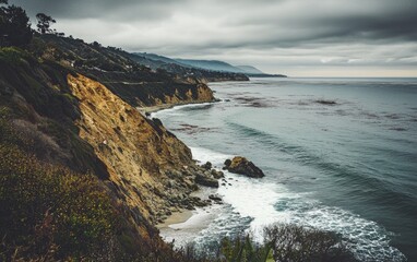 Obraz premium Coastal cliffs along a serene ocean with cloudy skies during a calm afternoon
