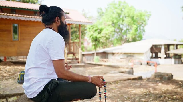 Religious guy sits by lotus position outdoor