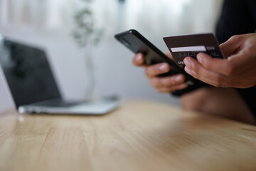 Hand holding credit card and using laptop. Businessman or entrepreneur working from home. Online shopping, e-commerce, internet banking, spending money, work from home concept.
