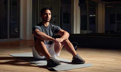 Thinking, fitness and relax with man in gym for workout, reflection and health at night. Exercise, sports center and wellness with person and resting in studio for strong, athlete and memory