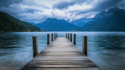 Obraz premium Wooden pier extending into a calm lake with mountains in the background
