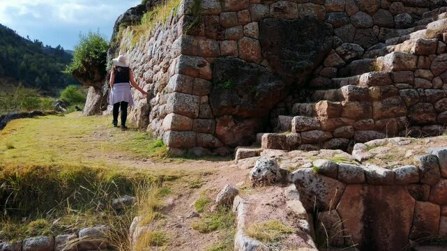 Close up, pan left view of stone stairways at Inkilltambo ruins, Cusco, Peru. Caucasian brunette woman tourists walks alongside terraced walls ====
