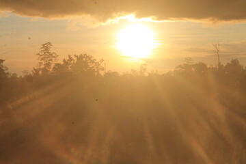 Its first rays of light shine down gently, illuminating a vast field, perhaps filled with wheat or...