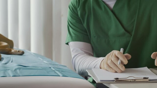 Cropped pan shot of unrecognizable specialist in green uniform filling medical form while inspecting yellow python in modern clinic
