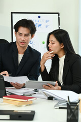 Photo of young office workers working together at the working desk with a computer laptop and digital tablet.