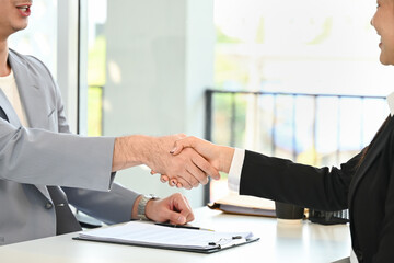 A man shakes hands with a woman in a business meeting.