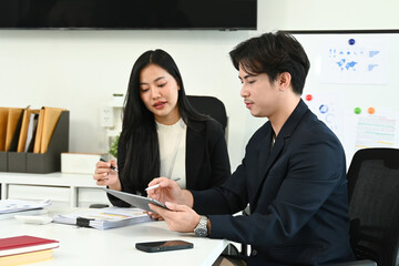Photo of young office workers working together at the working desk with a computer laptop and digital tablet.