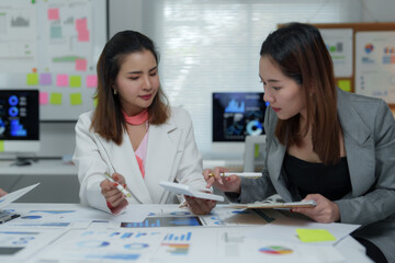 Businesswomen working together using calculator in office meeting analyzing charts and reports