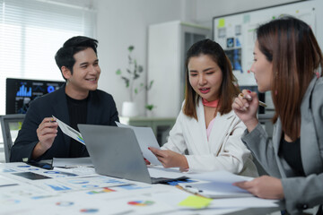 Asian businesspeople discussing documents and working on laptop in office meeting