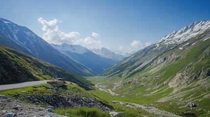 A winding road travels through a mountain valley under the bright sky