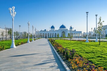Obraz premium Walkway to a white mosque with blue domes under a clear blue sky.