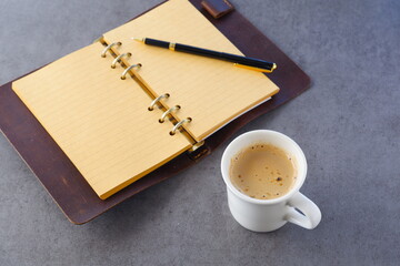 ミルクをたっぷり入れたコーヒー、カフェ・ラッテを飲みながら、システム手帳でデスクワークをしているイメージの写真素材
