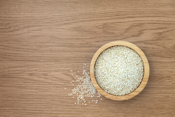 White sesame in a bowl on wooden texture background