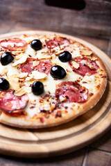 Pizza with salami and mozzarella cheese. Wooden background. Soft focus. Close up.