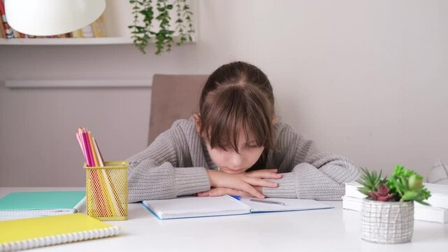 Tired, frustrated student is sitting at desk doing his homework. Learning difficulties, the concept of education. Student experiencing stress during homeschooling.