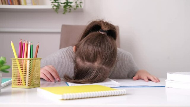 Tired, frustrated student is sitting at desk doing his homework. Learning difficulties, the concept of education. Student experiencing stress during homeschooling.