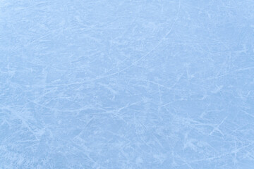 close-up view of an ice surface with multiple skate marks and scratches. The frozen texture suggests use in sports like hockey or figure skating.