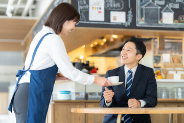 カフェでビジネスマンを接客する女性の店員