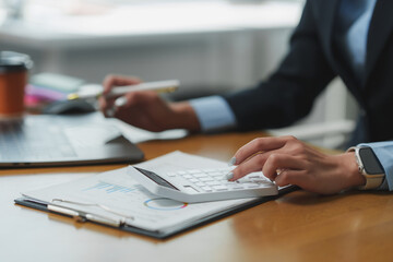 Businesswoman calculating tax using calculator in office