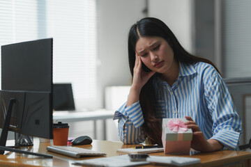 Sad businesswoman looking at a gift box at office desk