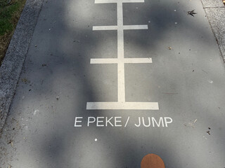 Markings on the tarmac of a playground have the words 'E Pike' and 'Jump'. Maori and English Language.New Zealand