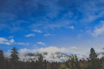 Snow-capped mountain peaks under a bright, expansive blue sky.