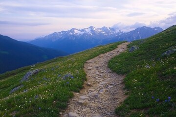 Fototapeta premium Winding path through lush green hills leading to majestic snowy