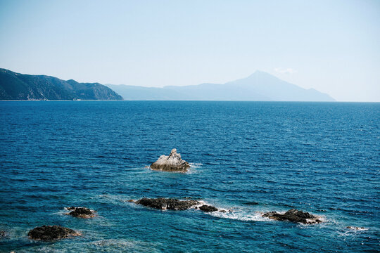 Serene Seascape with Rocky Shoreline and Distant Mountains
