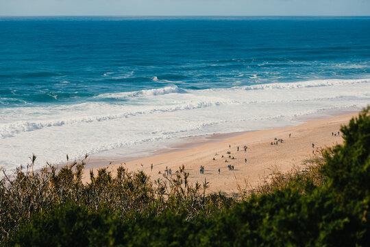A scenic view of Nazar&eacute; beach with waves and visitors