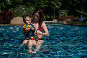 Naklejka premium A Caucasian woman and her one-year-old son swim in a pool.