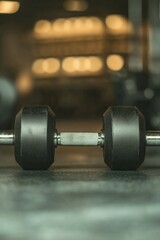 Naklejka premium Sleek dumbbell rests on gym floor, capturing focus with blurred