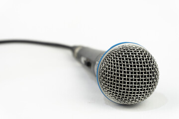A close-up shot of a dynamic microphone resting on a white surface, highlighting its mesh grill and sleek design.