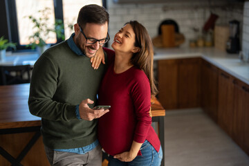 Naklejka premium Couple with pregnant woman make video call, taking selfie, spend leisure at home enjoy modern tech