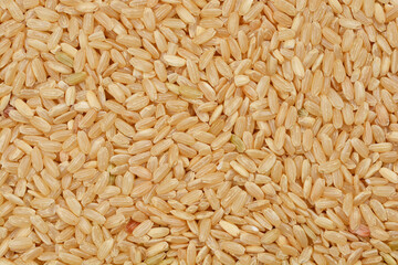 A close-up, overhead shot of a pile of brown rice grains showcases their natural texture and earthy color, emphasizing their wholesomeness and dietary value
