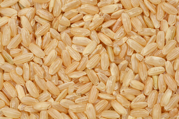 A close-up, overhead shot of a pile of brown rice grains showcases their natural texture and earthy...