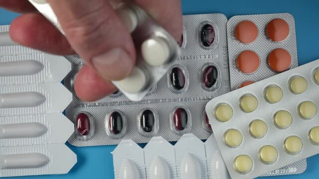 Hand of elderly man taking medicine for prostatitis. Tablets, pills and rectal suppositories for the treatment of prostate adenoma, frequent urination and erectile dysfunction. 4K video, rotating.