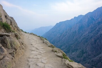 Fototapeta premium Winding path along rocky cliffs, surrounded by majestic mountain