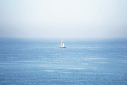 A lone white sailboat cruising at sea