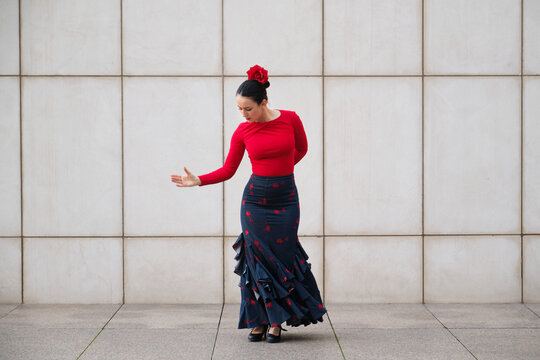 Flamenco dancer performing with red shirt and bata de cola at street