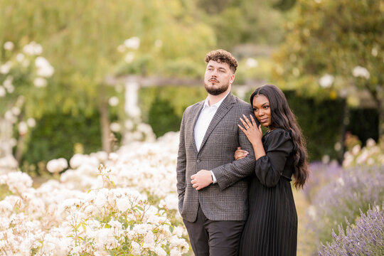 Stylish couple posing elegantly in a blooming garden