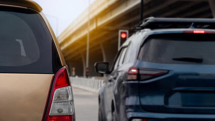Obraz premium Cars in traffic with a red traffic light visible. Background is blurred suggesting movement or distance with an elevated structure hinting at an overpass or bridge. Scene implies urban congestion.