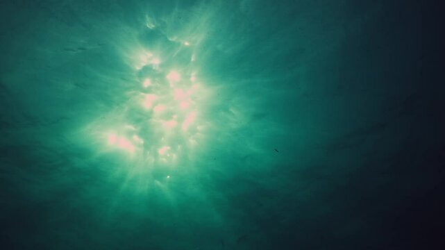 UK Diving abstract topside view of sun piercing through Ocean Green Water