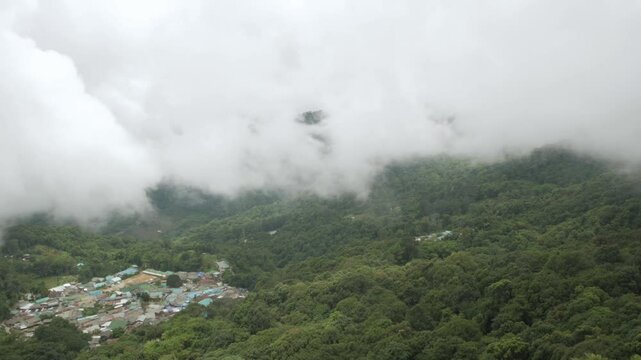aerial view from doi pui view point to the local village among the mountain range hill valley with white cloud and fog over the village in winter daytime